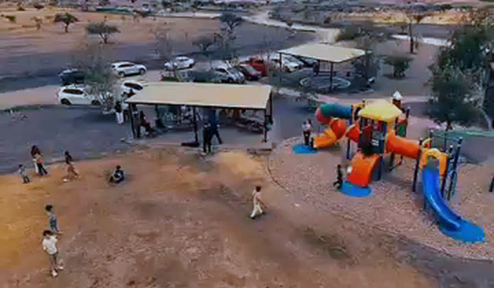 Vista aérea de la reunión dominical de Iglesia Soma Querétaro en Gran Parque Central, Bio Grand, Juriquilla: pérgola con mesas de madera y juegos infantiles